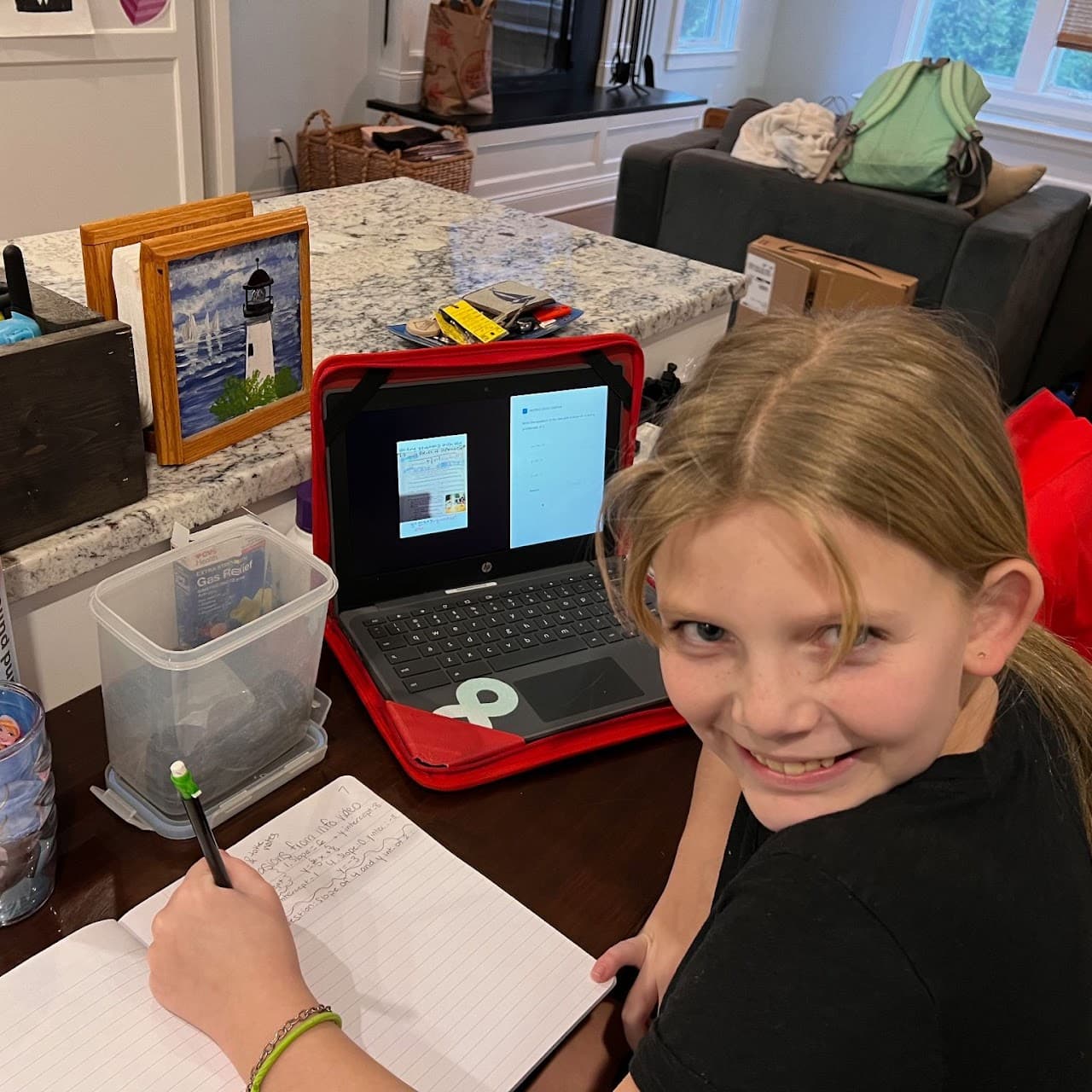 Student smiling while studying with a laptop and notebook at home